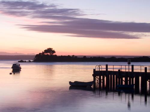 a dock with a boat in the water at sunset at Mercure Kangaroo Island Lodge in American River