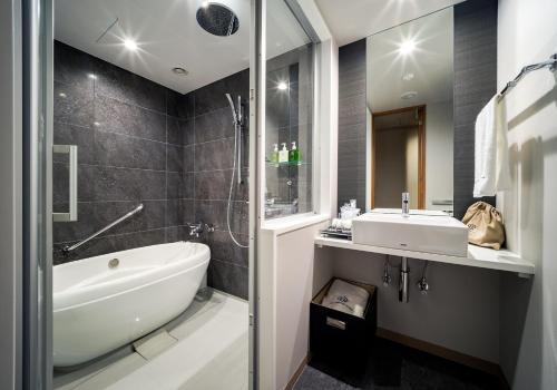 a bathroom with a tub and a sink and a shower at Daiwa Roynet Hotel Nagoya Taiko dori Side in Nagoya