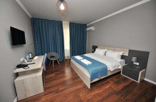 a bedroom with a bed and a desk and a television at Boho Tiflis Hotel in Tbilisi City