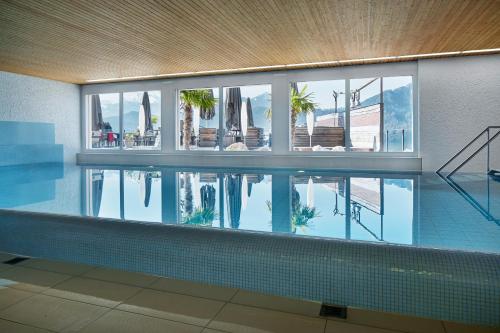 a swimming pool in a building with a reflection in the water at Hotel Alpenblick in Weggis