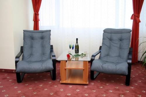 twee stoelen en een tafel met een fles wijn bij Hotel Calarasi in Călăraşi