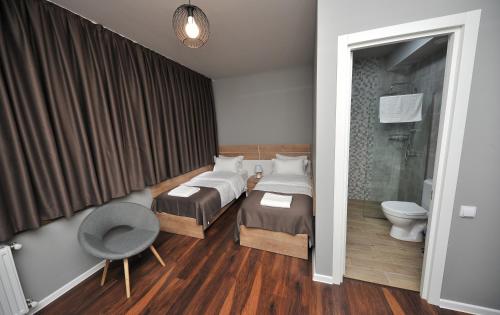 a bedroom with two beds and a chair and a toilet at Boho Tiflis Hotel in Tbilisi City