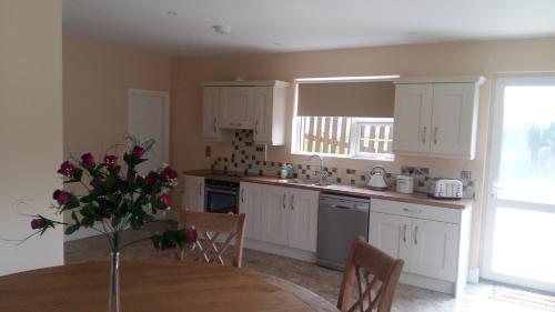 a kitchen with white cabinets and a table with a vase of flowers at killarney retreat in Killarney