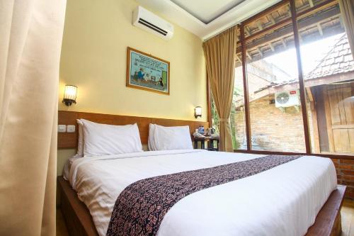 a bedroom with a large bed and a window at Cempaka Villa in Borobudur
