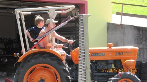 two people standing on a tractor in a garage at Wäldebauernhof in Gutach
