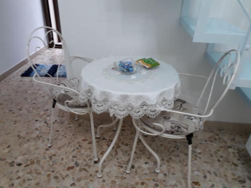 une table avec deux chaises et une table et des chaises blanches dans l'établissement La Casa Di Nicole, à Polignano a Mare