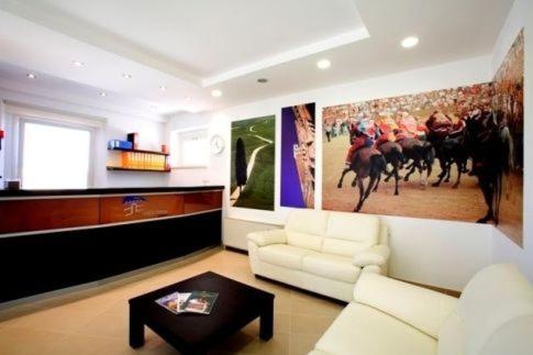 a living room with a white couch and a horse racing painting at Porta Pispini Residence in Siena