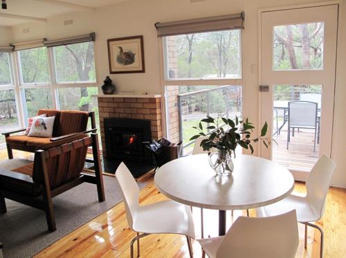 a living room with a table and chairs and a fireplace at Wattletree Cottage in Halls Gap