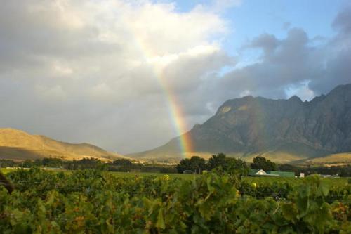 a rainbow in the middle of a field with mountains at Kuruma Farm Cottages in Worcester