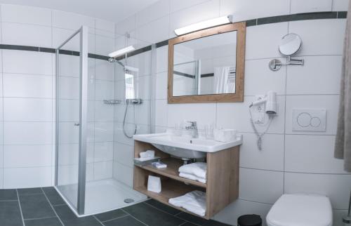 a bathroom with a sink and a shower and a mirror at Bierhotel - Hotel & Brauereigasthof Schneider in Essing