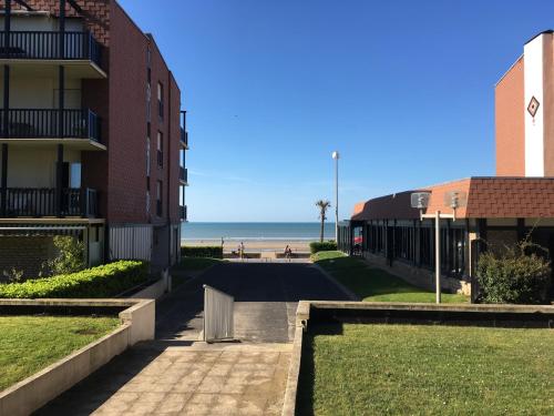 a walkway next to a building and the beach at Chez Fany et Ben in Cabourg