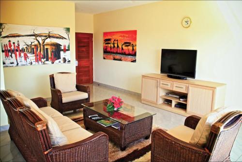 a living room with a flat screen tv and chairs at Voi Wildlife Lodge in Voi