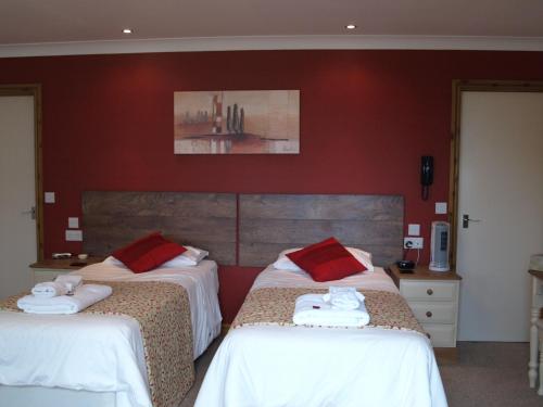 two beds in a hotel room with red walls at Spanhoe Lodge in Harringworth