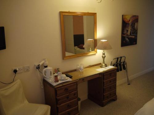 a room with a desk with a mirror and a lamp at The Lodge in Barnby Dun