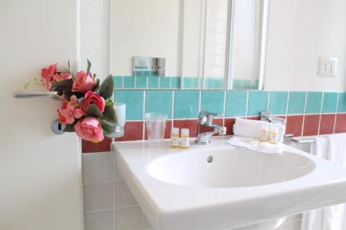 baño con lavabo y jarrón de flores en AHR Leonis Residence La Maddalena, en La Maddalena