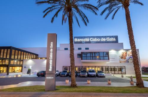 a building with palm trees in front of it at Barceló Cabo de Gata in Retamar