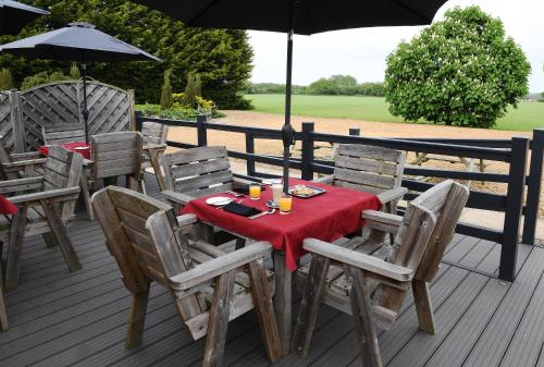 a table and chairs on a deck with an umbrella at Spanhoe Lodge in Harringworth