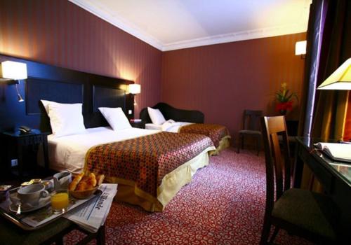 パリにあるコンベンション モンパルナスのベッド2台とテーブルが備わるホテルルームです。