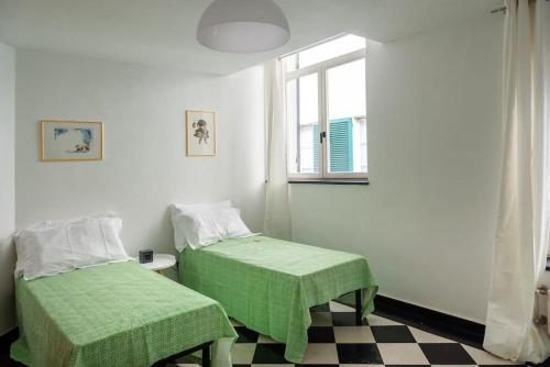 Cette chambre comprend 2 lits avec des draps verts et une fenêtre. dans l'établissement San Matteo 23, à Gênes