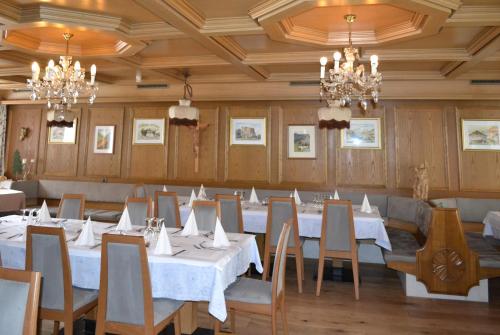 a dining room with white tables and chairs and chandeliers at Hotel Alpenblick in Sarntal
