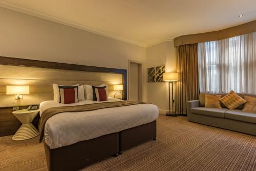 ロンドンにあるThistle London Holbornの大きなベッドとソファが備わるホテルルームです。