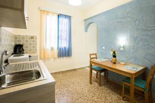 uma cozinha com uma mesa, um lavatório, uma mesa e cadeiras em Vassos Apartments em Lindos