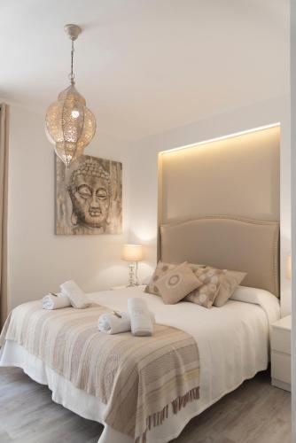 a white bedroom with a bed with towels on it at Cosy Flat - City Center - Parking free in Málaga