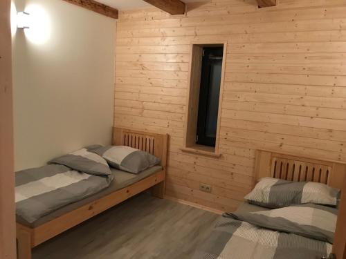 two beds in a room with wooden walls at Dom Mazurski Tumiany 3 B in Tumiany