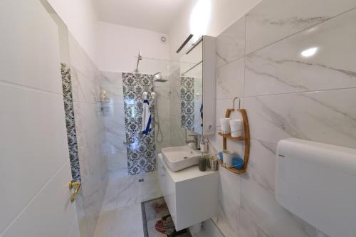 uma casa de banho branca com um lavatório e um espelho em Apartment Popek Opatija em Opatija