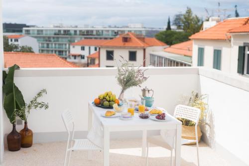 Cozy apartment - Historic Center of Funchal, Madeira في فونشال: طاولة بيضاء مع فاكهة على شرفة