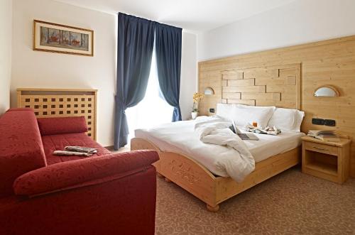 sypialnia z łóżkiem i czerwonym krzesłem w obiekcie Hotel Europa w Madonna di Campiglio