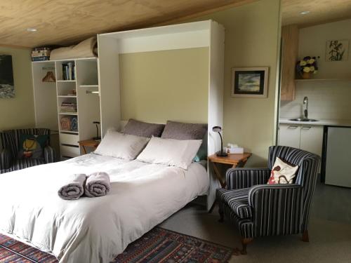 a bedroom with a large white bed and two chairs at The Nook in Arthur's Pass