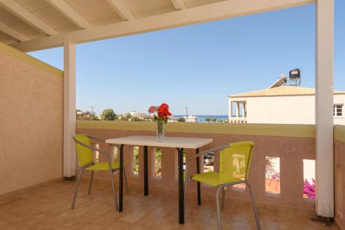 una mesa y sillas en un balcón con vistas en Hotel Kiklamino en Kalamaki Heraklion