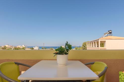a white table with a potted plant on a balcony at Hotel Kiklamino in Kalamaki Heraklion