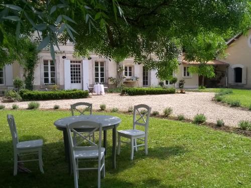 a table and chairs in front of a house at Le Domaine Des Platanes in Bourg-Charente