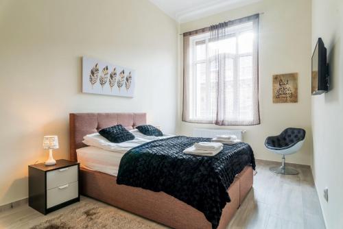 1 dormitorio con cama, ventana y silla en K11 Exclusive Apartment at Szimpla, en Budapest