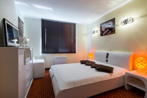 um quarto com uma cama branca e uma televisão em Luksusowe apartamenty Przy Plaży-Continental em Krynica Morska