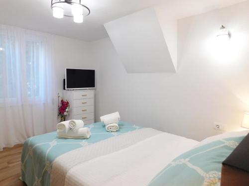 a white bedroom with a bed and a tv at Studio apartment Milla in Split