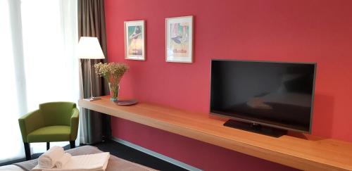 a living room with a flat screen tv on a red wall at Bata Club Haus in Möhlin