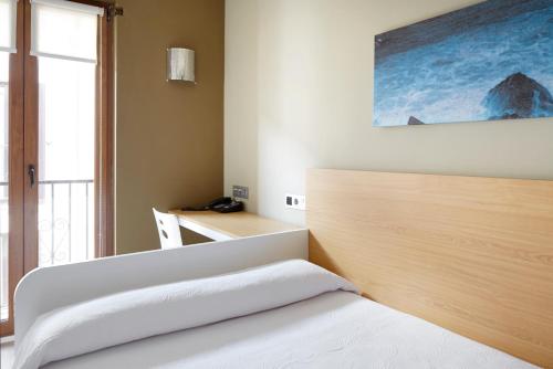 a bedroom with a bed and a desk with a window at Hotel Olatu in Zarautz