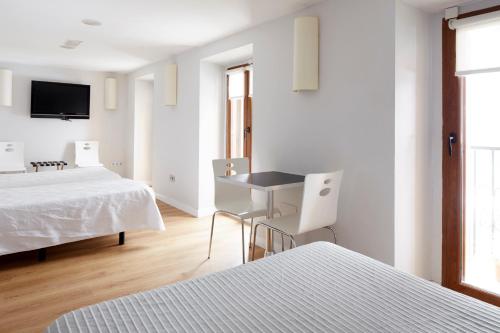ein weißes Zimmer mit 2 Betten sowie einem Tisch und Stühlen in der Unterkunft Hotel Olatu in Zarautz