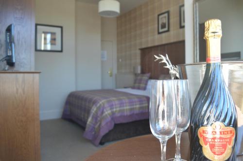 a room with a bed and a table with two wine glasses at Beaufort Hotel in Inverness