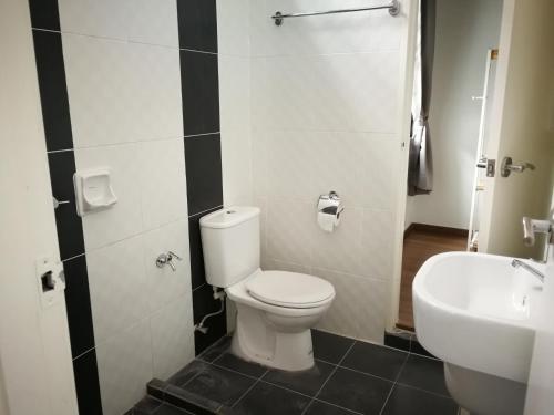 a bathroom with a white toilet and a sink at Happy Holiday home in Balik Pulau