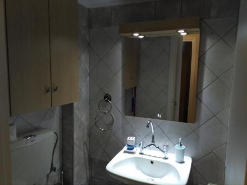 a bathroom with a sink and a mirror and a toilet at Zefi's Apartment in Nea Peramos
