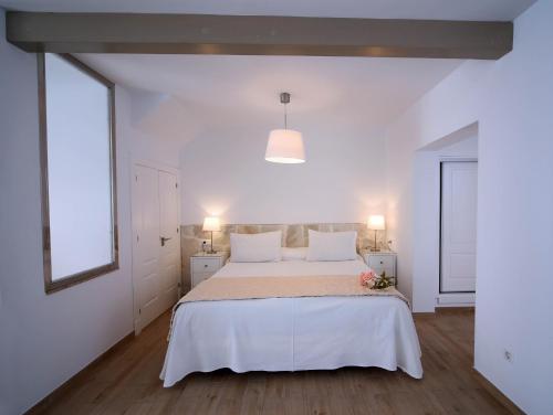 a white bedroom with a large bed with white sheets at Hotel Casa Rosa in Benalmádena