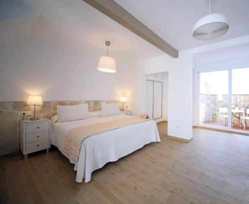a white bedroom with a bed and a large window at Hotel Casa Rosa in Benalmádena