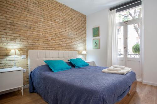 a bedroom with a bed with blue pillows and a brick wall at Casa Marcellino Valencia Centro in Valencia