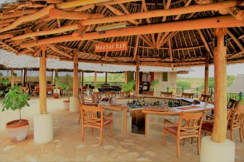 a restaurant with a bar with chairs and tables at Manyatta Camp in Voi
