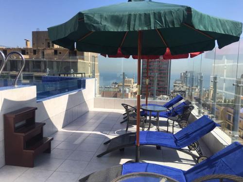 um pátio com uma mesa, cadeiras e um guarda-sol em Midtown Hotel & Suites em Beirute