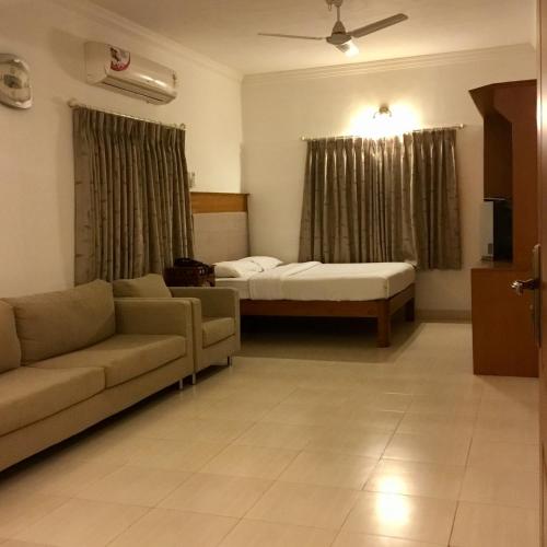 a living room with a couch and a bed at Sai Towers in Puttaparthi